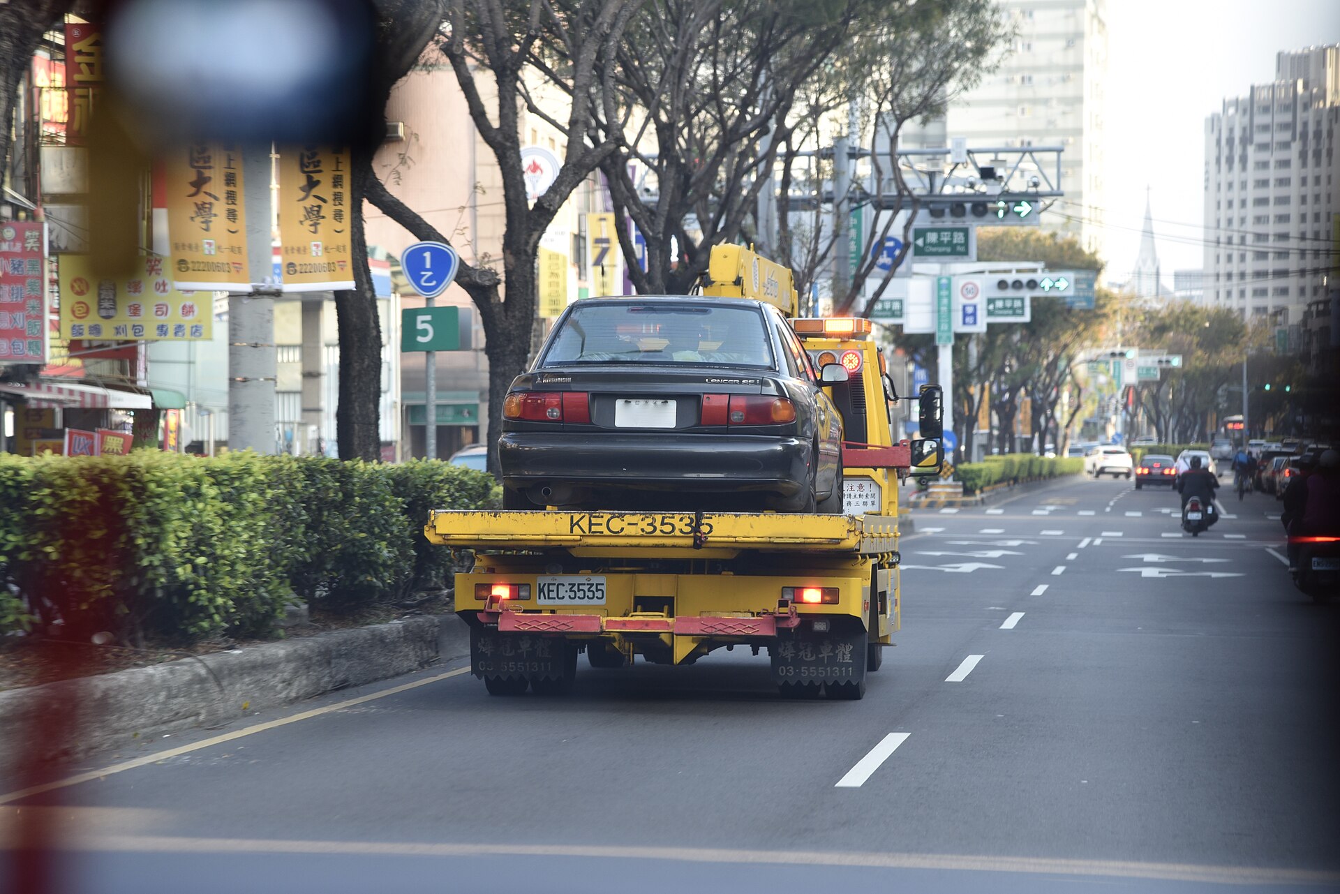 Trak tunda membawa kereta di atas jalan raya